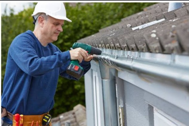 Contractor securing a gutter bracket with a cordless drill
